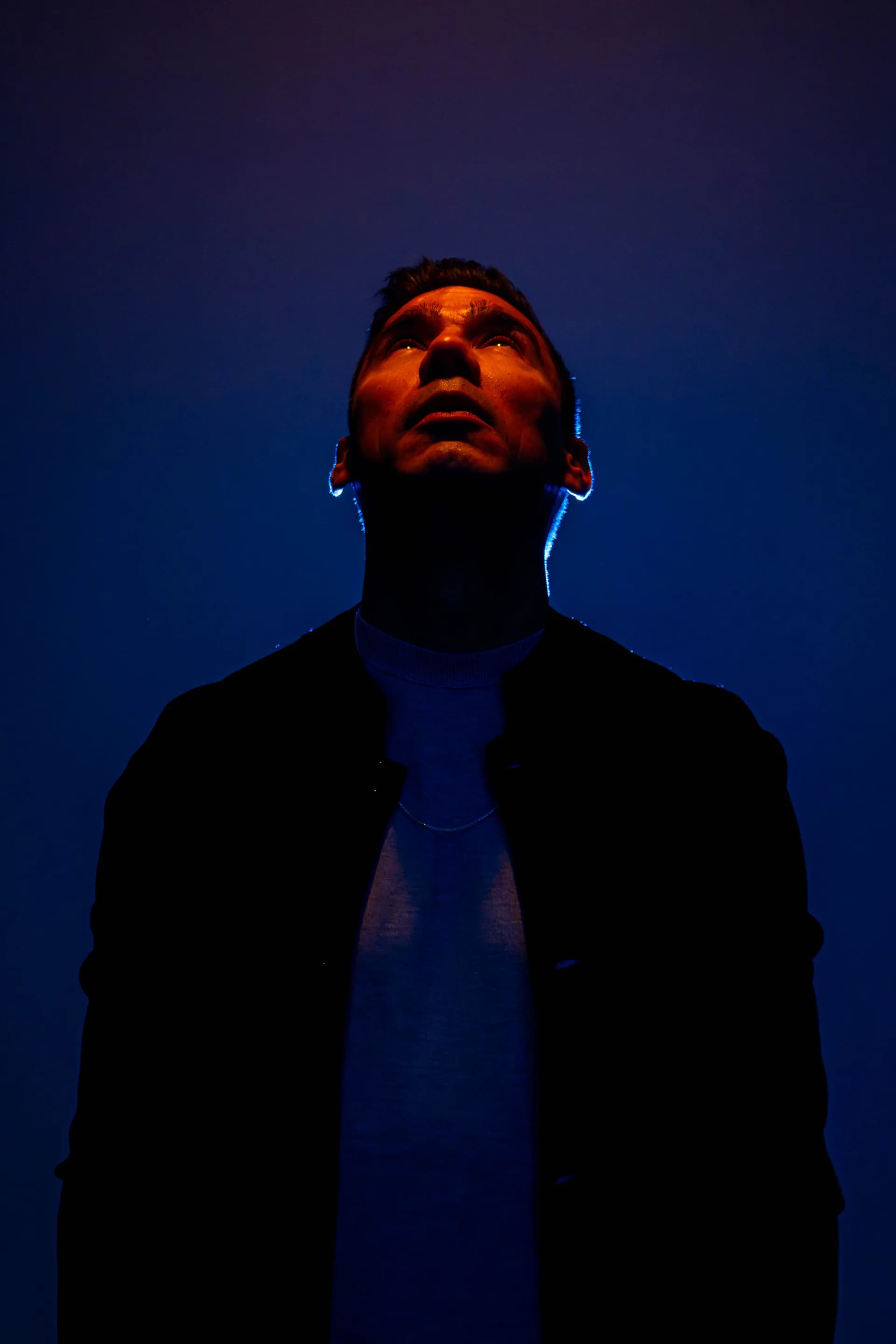 Miguel Cupido — face emerging from darkness, looking up into warm light